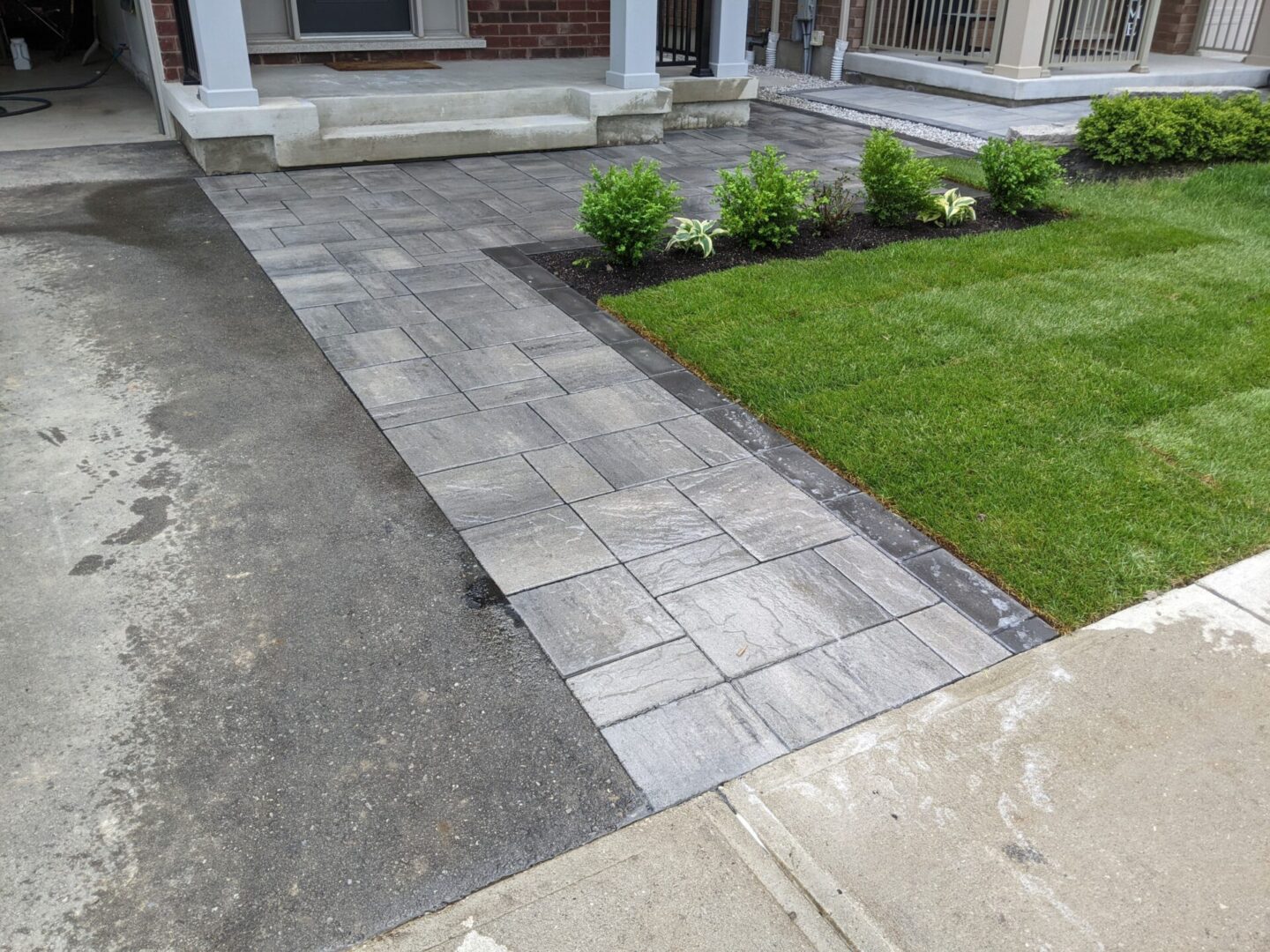 A walkway with grass and bushes in front of it.